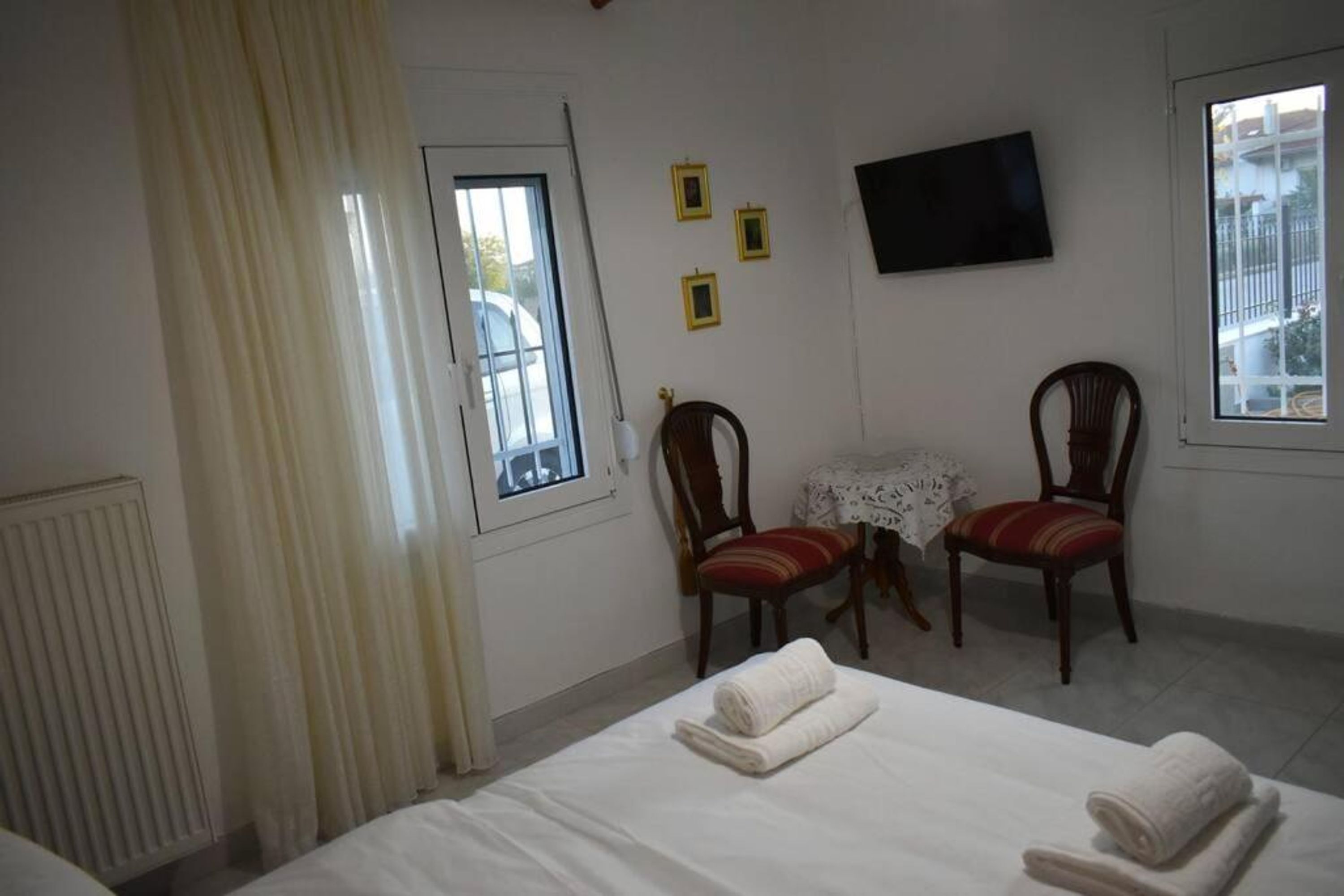 Ein Hotelzimmer mit einem Bett, zwei Stühlen, einem kleinen Tisch und einem Fernseher an der Wand.