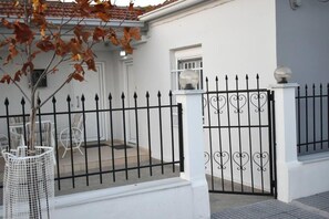A white building with a black wrought iron gate and a small window. - Avli Guesthouse (Trikala)