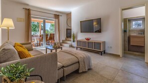 A modern living room with a sofa, coffee table, and a TV mounted on the wall.