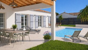 Ein überdachter Außenbereich mit Pool, Liegestühlen und einem Esstisch mit Stühlen.