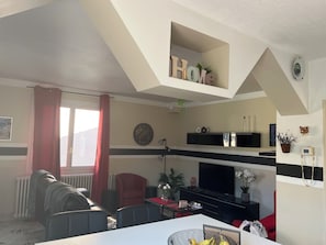 Un salon comprenant un canapé, une table à manger, un téléviseur et une cheminée.