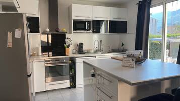A modern kitchen with white cabinets, a built-in oven, microwave, and a large island with a sink.