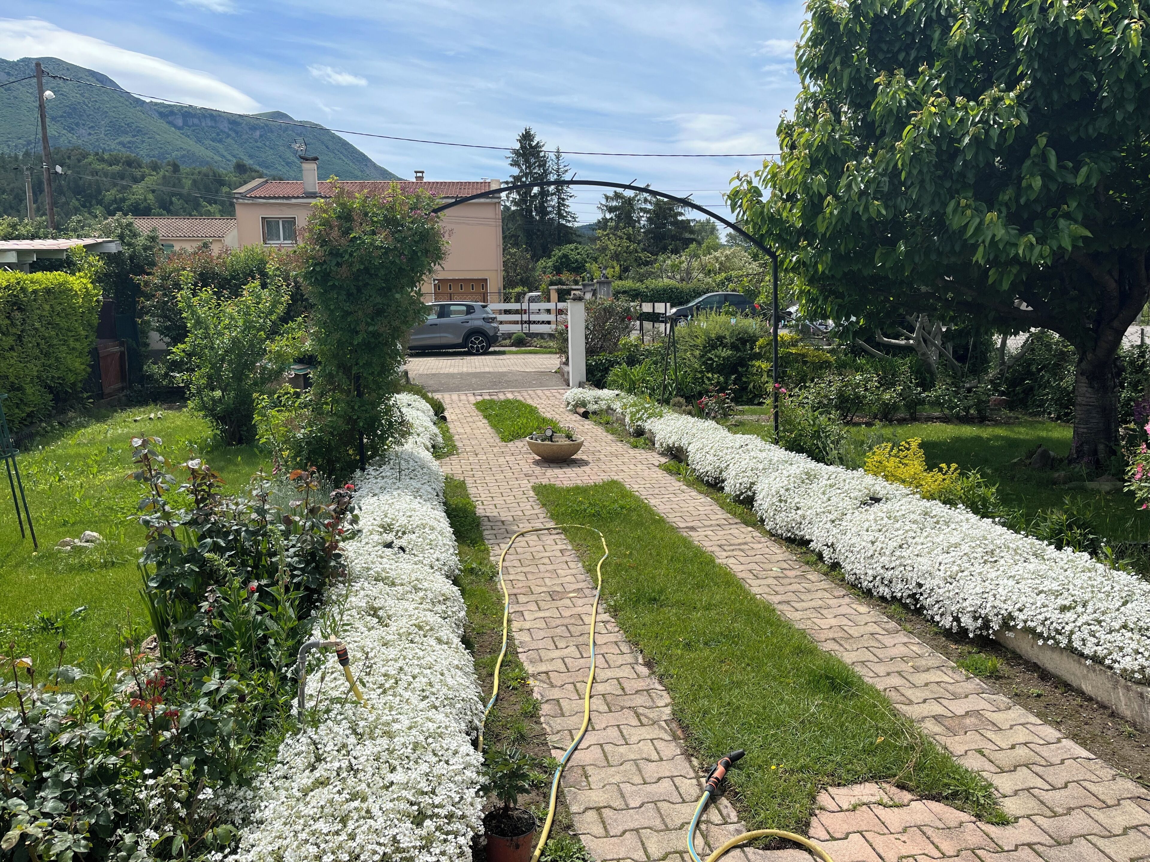 A garden pathway leading to a house with a car parked in the driveway.