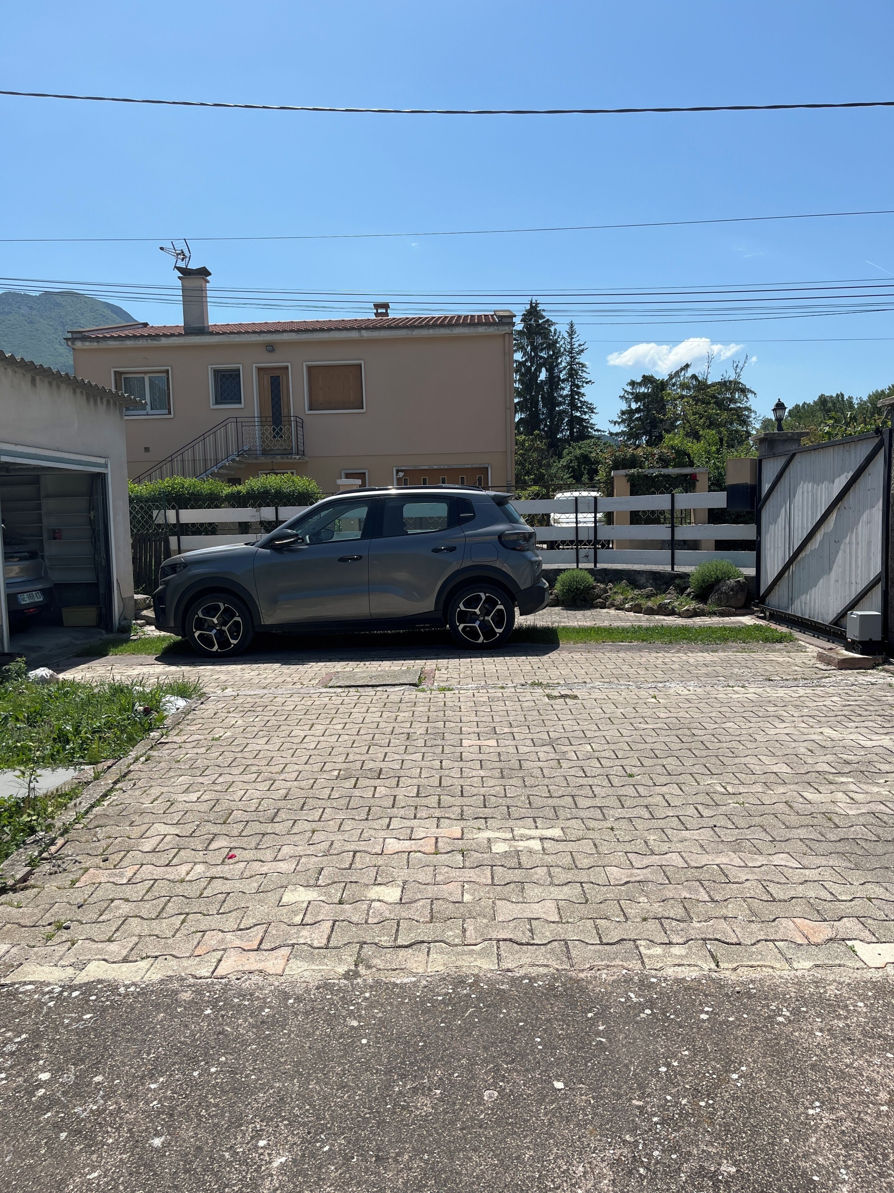 A car parked in a driveway with a house in the background.