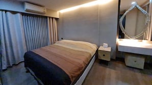 Een hotelkamer met een bed, nachtkastje en een spiegel met ingebouwde haardroger.
