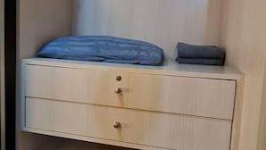 Een slaapkamer met een bed, nachtkastje en lade.