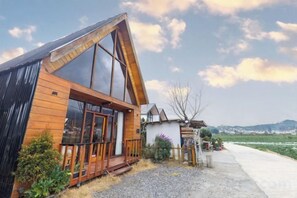 Una cabaña de madera con techo inclinado, ventanas grandes y un porche.