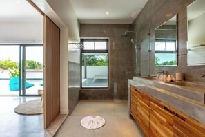 A modern bathroom with a large mirror, wooden cabinets, and a shower area. - Villa Nirvana (Koh Samui)