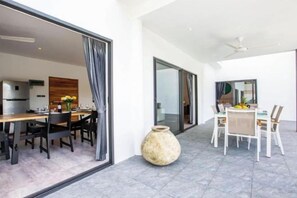 Un espace repas moderne avec une grande table et des chaises, un vase et une vue sur la cuisine.