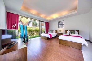 A hotel room with two beds, a TV, and a balcony with a view of greenery. - Baan Benjamart (Koh Samui)