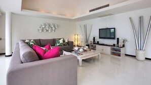 A modern living room with a sofa, coffee table, TV, and decorative elements. - Baan Benjamart (Koh Samui)