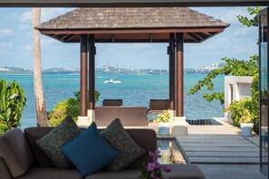 A covered outdoor seating area with a view of the sea and boats. - Baan Benjamart (Koh Samui)