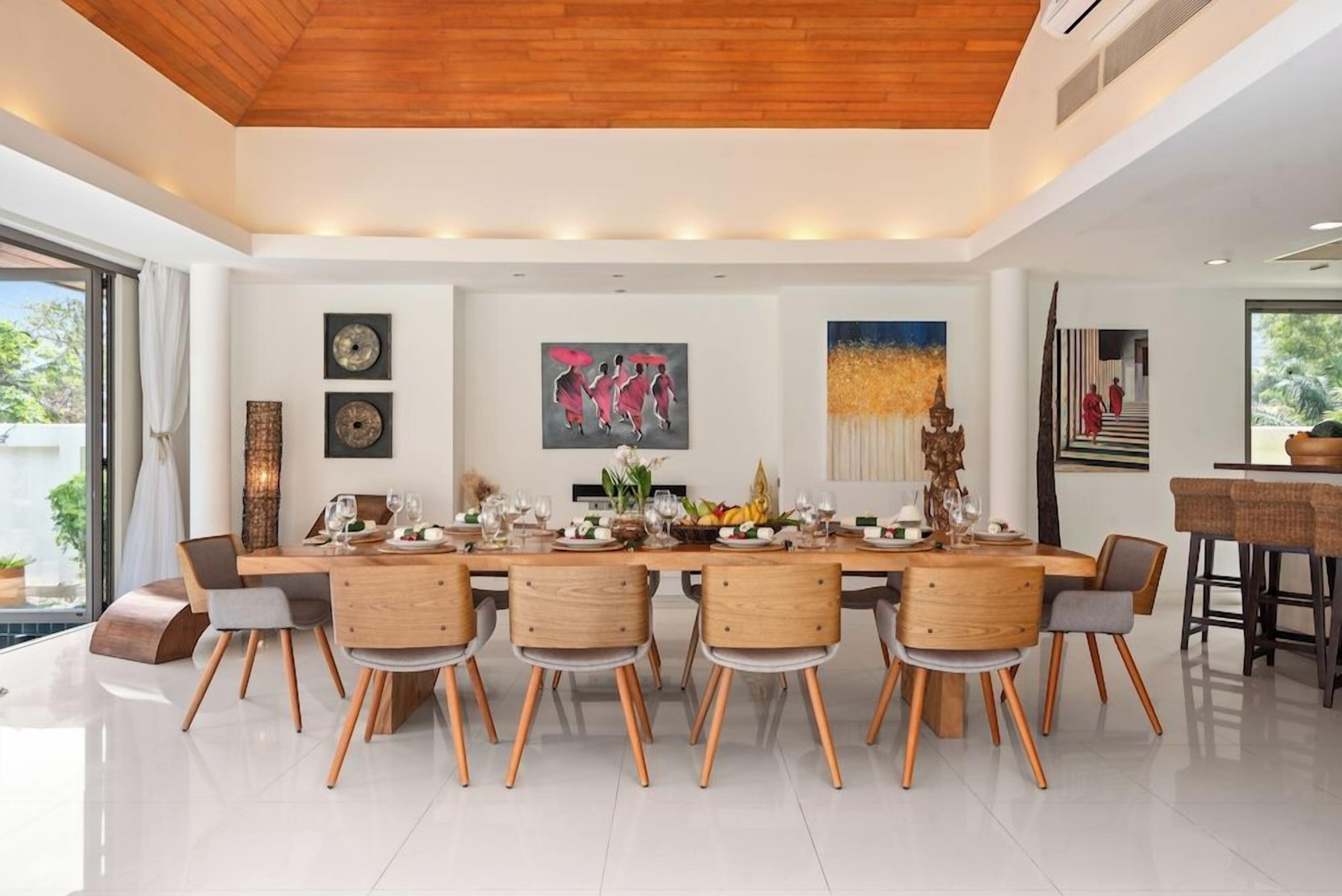 Uma sala de jantar moderna com uma mesa de madeira comprida, seis cadeiras e diversos jogos de louça.