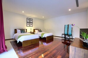 A hotel room with two beds, a desk, a chair, and a plant. - Baan Benjamart (Koh Samui)
