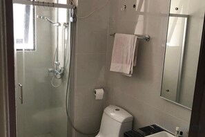 Une salle de bain avec une douche à parois de verre, des toilettes, un lavabo et un porte-serviettes.