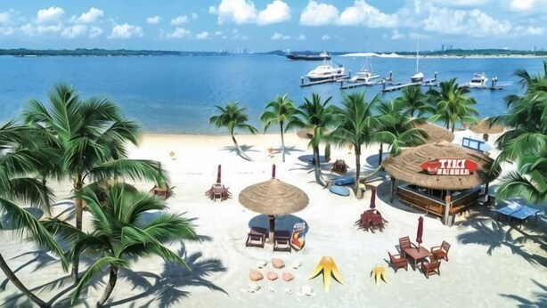 Una playa con palmeras, un bar con techo de paja y barcos en el agua.