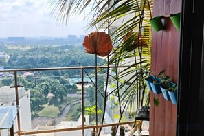 Ein Balkon mit Blick auf eine Stadtlandschaft, eine Palme und Kübelpflanzen.