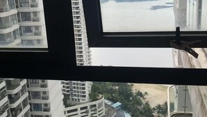 Vista desde una ventana de un edificio de gran altura, con varios balcones, sobre una masa de agua y un edificio curvo con piscina.