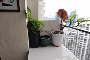 Un balcon agrémenté de plantes en pot et offrant une vue sur le paysage urbain.