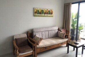 Un salon comprenant un canapé, deux fauteuils, une table basse et un tableau accroché au mur.