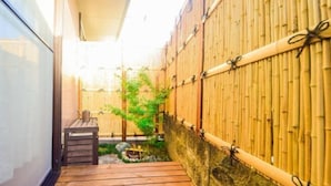 A narrow wooden deck with a stone wall on one side and a bamboo fence on the other. - Ryokan -Ryo- by Tranova (Tokyo)