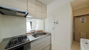 A compact kitchen with a stove, sink, and built-in oven. - Ryokan -Ryo- by Tranova (Tokyo)