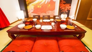 A dining table set with various dishes and utensils, a red cushioned bench, and a traditional Asian-style wall painting. - Ryokan -Ryo- by Tranova (Tokyo)