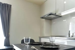 A small, modern kitchen with a dining table, two glasses, and a spoon. - Ryokan -Ryo- by Tranova (Tokyo)