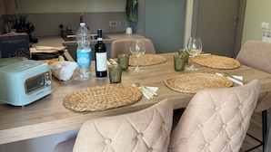 Una cocina moderna con una isla central, dos lámparas colgantes y un comedor con cuatro sillas acolchadas.