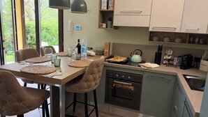 Una cocina moderna con comedor, que incluye un horno empotrado, un hervidor y diversos utensilios de cocina.