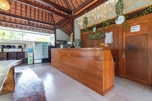 Un área de recepción con mostrador de madera, un reloj y una puerta con la leyenda 'Solo personal'.