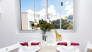 Une table à manger dressée avec de l’argenterie blanche, des serviettes rouges et des verres transparents, agrémentée d’un vase de fleurs et d’une décoration représentant une girafe dorée.