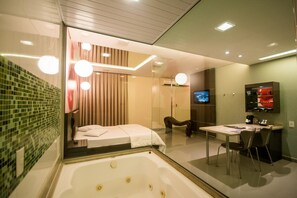 Un baño moderno con cabina de ducha de vidrio, bañera, tocador con espejo y televisor montado en la pared.