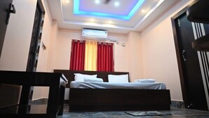 Une chambre à coucher avec un lit, un ventilateur de plafond, un appareil de climatisation et une fenêtre avec des rideaux rouges.