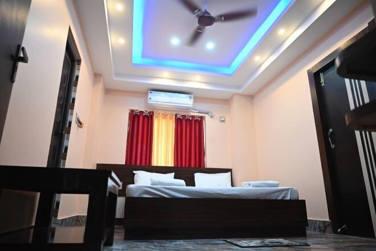 Une chambre à coucher avec un lit, un ventilateur de plafond, un appareil de climatisation et une fenêtre avec des rideaux rouges.