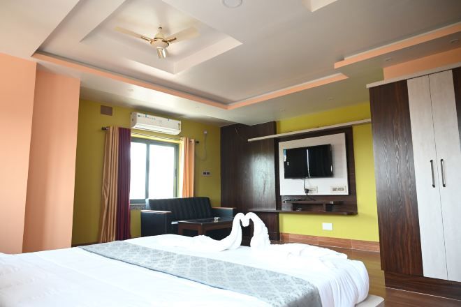 Habitación de hotel con cama, escritorio, silla, televisor y armario.
