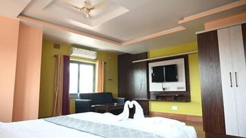 Habitación de hotel con cama, escritorio, silla, televisor y armario.