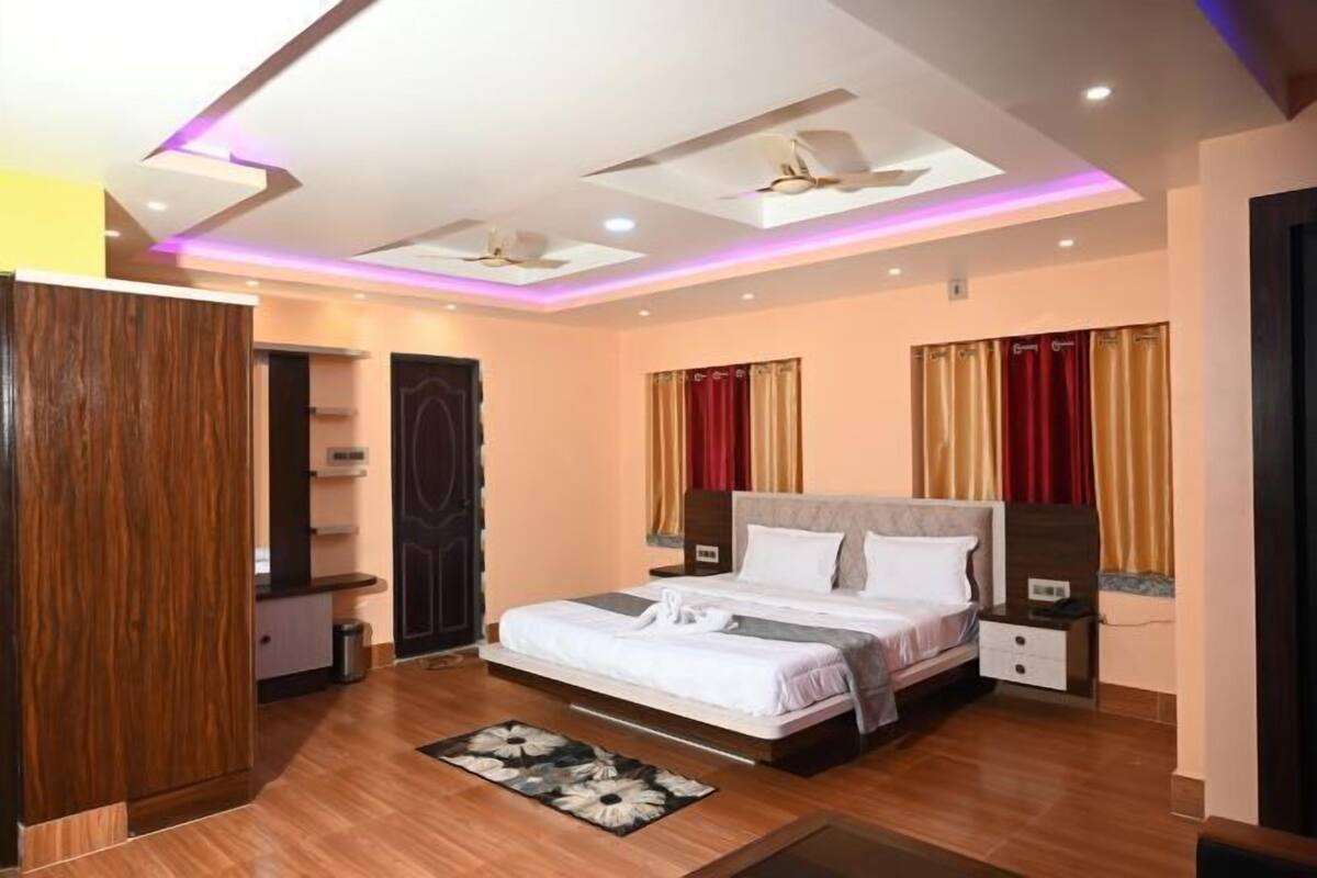Une chambre d’hôtel équipée d’un lit, de tables de chevet, d’une armoire, d’un ventilateur de plafond et d’un éclairage moderne.