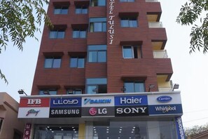 A multi-story building with a commercial ground floor featuring various brand logos. - Hotel Tulusi Inn (Bolpur)