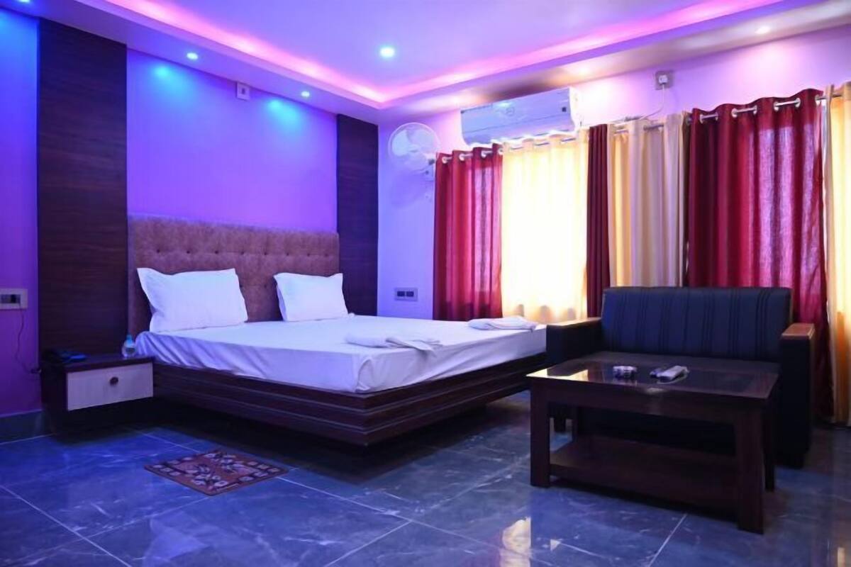 Une chambre d’hôtel avec un lit, une table basse, une table de chevet et une fenêtre avec des rideaux.