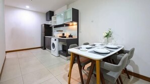 A compact kitchen with modern appliances, a dining table with chairs, and a small seating area. - Specious Luxury 2 bedrooms Apt. (Chiang Mai)