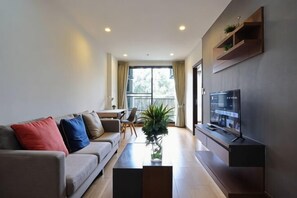 Una sala de estar moderna con sofá, mesa de centro, televisor y vistas al balcón.