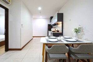 A modern hotel room with a dining area, a bed, and a kitchenette. - Specious Luxury 2 bedrooms Apt. (Chiang Mai)
