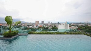 A rooftop pool with a cityscape view. - Specious Luxury 2 bedrooms Apt. (Chiang Mai)