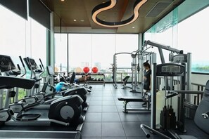 Ein Fitnessstudio mit Cardiogeräten, Krafttrainingsgeräten und Blick auf die Stadt.
