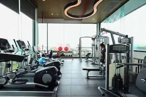 A gym with cardio machines, weightlifting equipment, and a view of the city. - Specious Luxury 2 bedrooms Apt. (Chiang Mai)