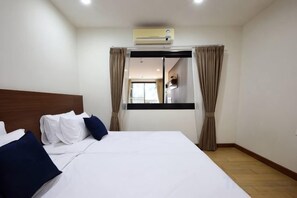 A hotel room with a bunk bed, a flat bed with white linens, a ceiling air conditioner, and a view of the hallway. - Specious Luxury 2 bedrooms Apt. (Chiang Mai)