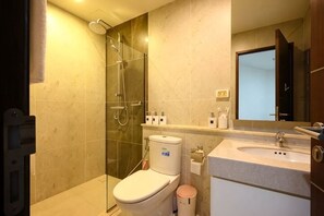 A modern bathroom with a glass shower enclosure, a toilet, a sink, and a mirror. - Specious Luxury 2 bedrooms Apt. (Chiang Mai)