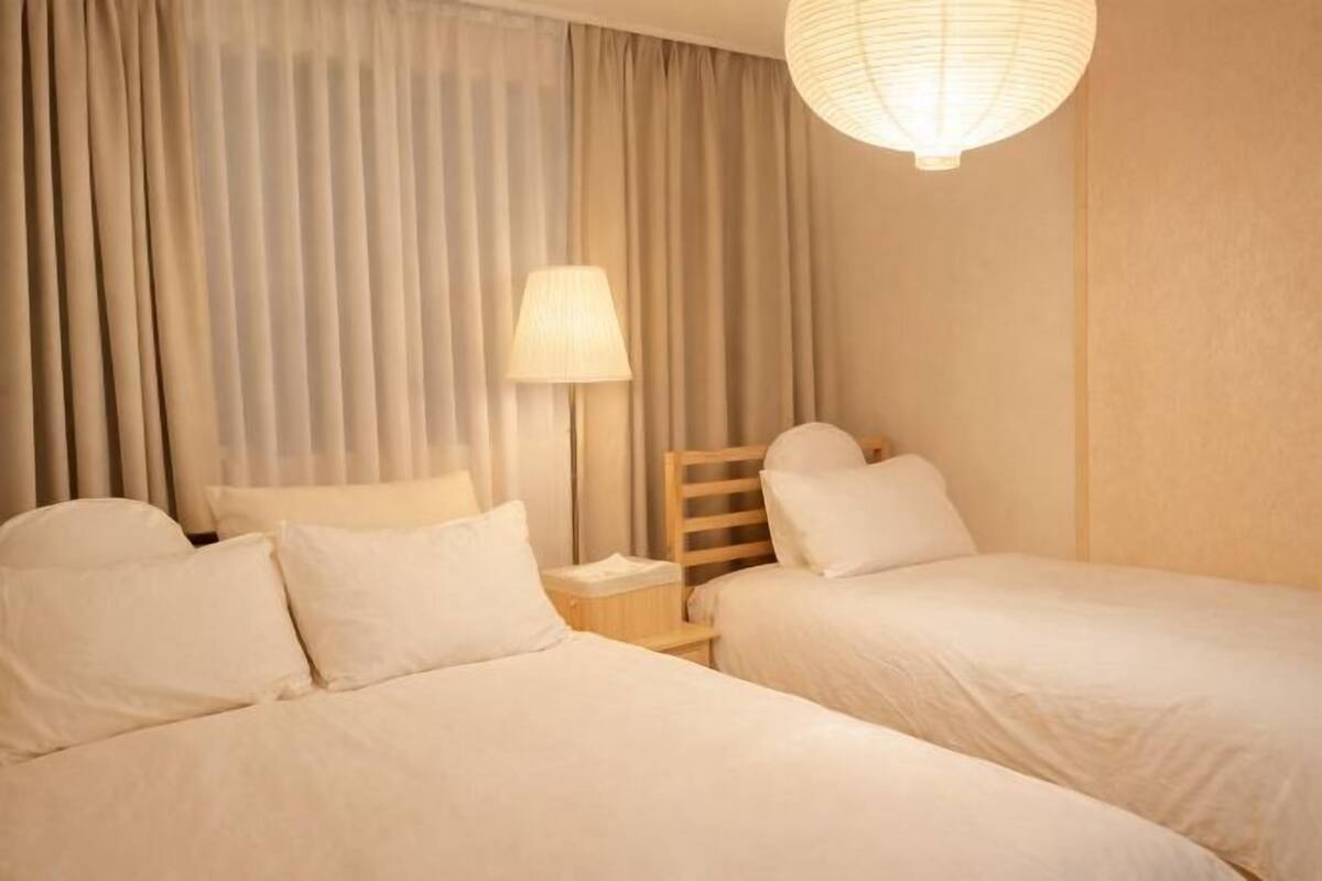 Ein Hotelzimmer mit zwei Betten, einem Nachttisch, einer Lampe und einer Pendelleuchte.