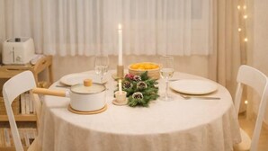 A round table with a white tablecloth, a candle, a fruit bowl, and a small Christmas tree decoration. - Turtle Stay Seoul-- the Center of Seoul #Cozy Apartment (Seoul)